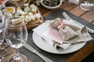 Obraz na płótnie Canvas Plate with linen napkin and pouch gift. Luxury wedding reception in restaurant. Stylish decor and adorning. Tables served with beautiful dishes and delicious food