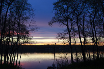 Obraz premium Beautiful sunset with silhouetted trees on Struthers Lake, Saskatchewan