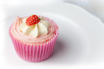 Pink strawberry cupcake on white plate