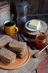 Healthy food concept. Breakfast with crispbreads, butter, jam, coffee. Flatbread crackers with sesame, flax seed, pumpkin and sunflower seeds. Diet crispy cookies. Snack gluten-free. Copy space