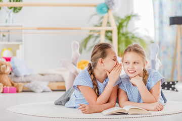 Mischievous twin sisters whispering secrets