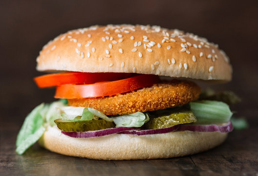 fresh tasty fishburger and french fries on wooden table