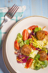 Colorful fresh vegetable salad with meatballs on rustic background