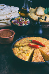 Cornbread and other mexican food - tacos, salsa with tomato, red onion, lime, cilantro, corn and hot pepper sauce, empanadas. Copy space.