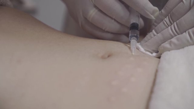 Hand holding syringe and injected into the stomach. Woman is getting stoch beaty tratment.