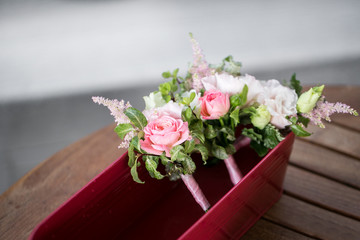 Flower composition, wedding bracelet of pink rose with ribbon and groom boutonniere on wooden table