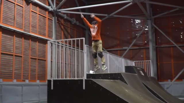 A man on rollers jumps on the railing on the ramp jumps down, slow motion
