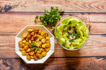 Fried potato balls with parsley and lettuce on wooden background