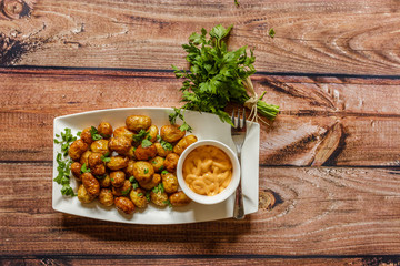 Fried potato balls with parsley and sauce on wooden background