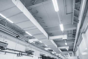 White Industrial Air duct from air conditioner cooling pipe with plumbing at ceiling in large industrial hall. - obrazy, fototapety, plakaty
