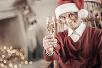 For me. Happy pensioner wearing Christmas hat and raising right hand while posing on camera