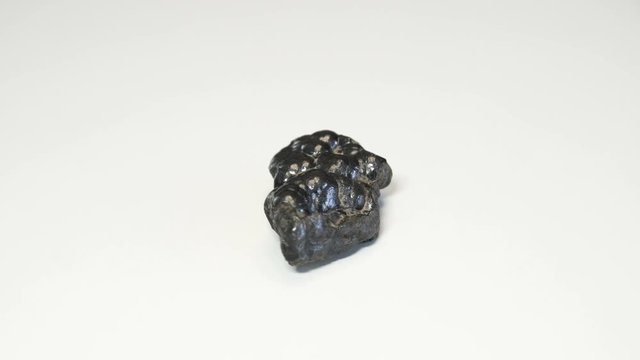 Macro shot of hematite mineral isolated over white background and spinning around
