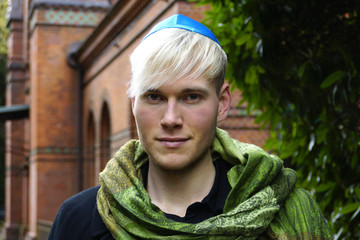 Junger Mann mit Kippa vor einer Synagoge