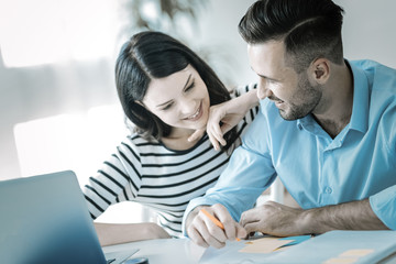 Lovely moment. Merry positive two colleagues smiling while dealing with documentation and flirting