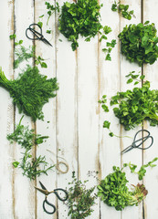 Fototapeta na wymiar Flat-lay of bunches of various fresh green herbs. Parsley, mint, dill, cilantro, rosemary, thyme over wooden background, top view, copy space, vertical composition. Healthy vegan cooking concept