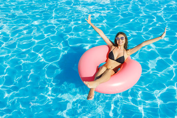 bikini girl with sunglasses relaxed on pink inflatable pool ring