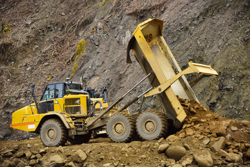 Heavy articulated dump truck work at a huge dam construction site