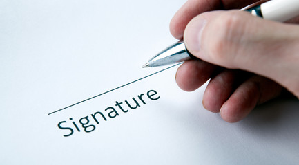 One document with a place for a signature and a hand of a man with a pen