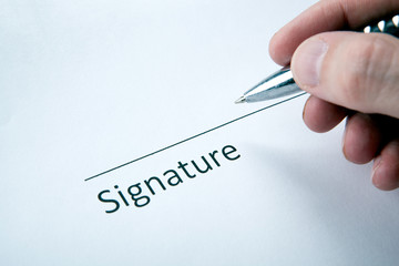 One document with a place for a signature and a hand of a man with a pen