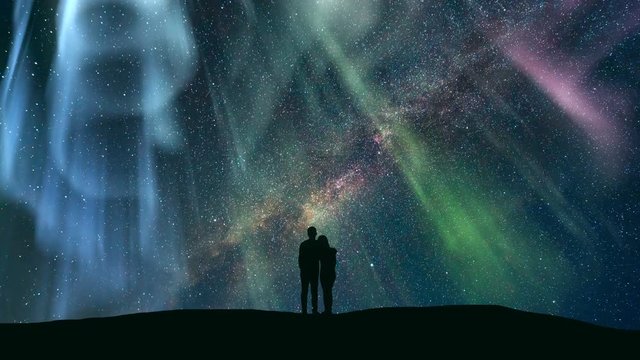 The couple standing against the northern light with a northern light. time lapse