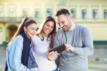 Group of smiling friends with digital tablet outdoor