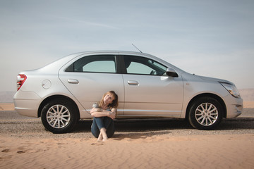 Girl have rest near car in desert