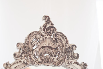 Element of old wooden carved frame on mirror.Bright interior. White frame with the effect of aging