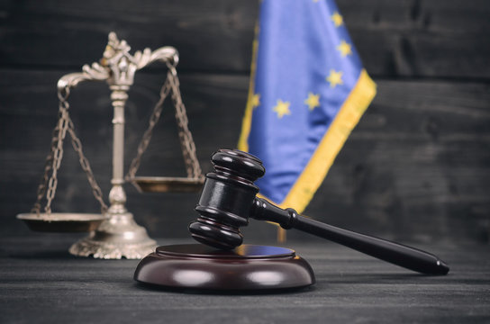 Scales of Justice, Judge Gavel and Flag of the European Union on a wooden background.