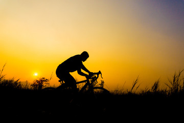 Silhouette of cyclist with friend in motion on the background of beautiful sunset