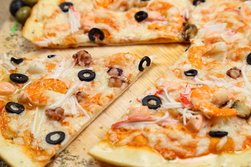 pizza thin olive shrimp crabs on a wooden stand macro photography