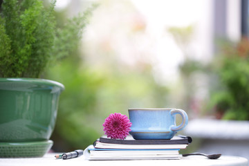 Blue vintage cup and flower with notebooks at outdoor