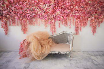 Old carved daybed with soft upholstery against a white wall decorated with pink flowers. Gorgeous...