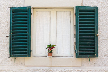 Window in an old house decorated with flower pots and flowers