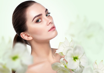 Obraz na płótnie Canvas Beautiful young woman with clean fresh skin . Cosmetology , beauty and spa concept. Beauty skin female face with a flower