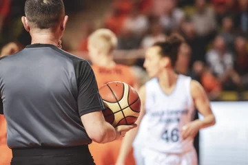 Fototapeten Referee holds the ball during women basketball match © Dziurek
