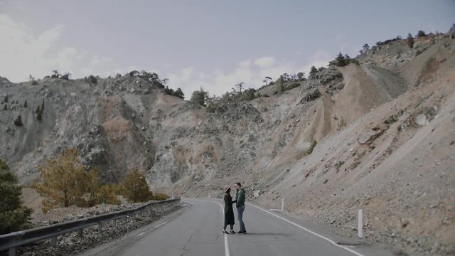 Stylish young couple walking on the mountain road