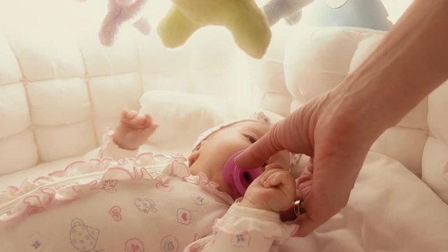 Giving pacifier to fussy baby in the cot