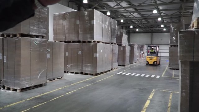 Lift truck in factory. Clip. Wholesale logistic, loading, shipment and people concept - man with loader carrying cargo at warehouse
