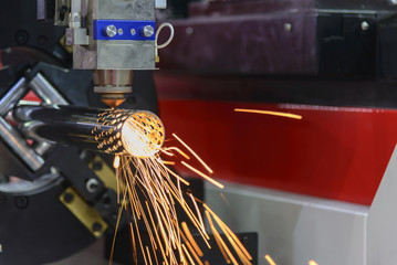 The CNC laser cutting machine cutting the stainless tube with the sparking light.