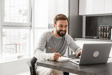 Fototapeta premium Portrait of a happy young man working on laptop