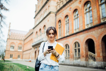 Student girl read something on smartphone outdoor in the campus