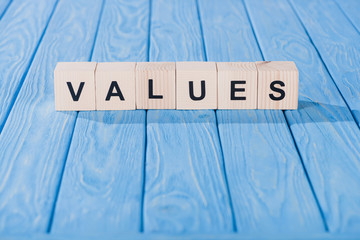 close up view of values word made of wooden blocks on blue tabletop
