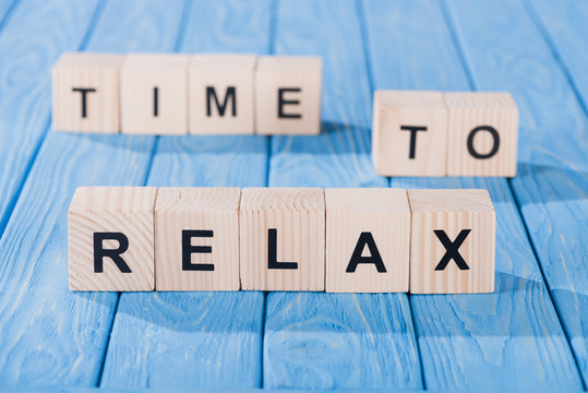 close up view of arranged wooden blocks into time to relax phrase on blue wooden surface