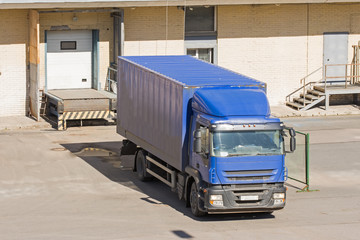 Truck loading goods, cargo, warehouse with doors.