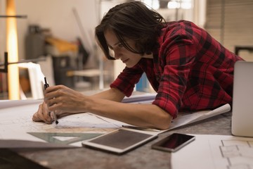Female engineer using compass in workshop