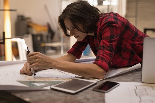 Female engineer using compass in workshop