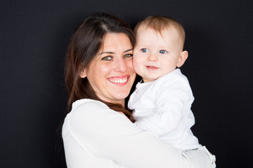 portrait of happy mother and son hugging in studio on black