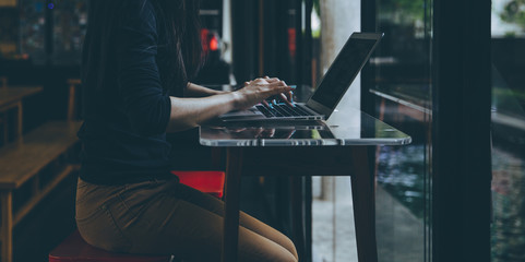 Beautiful young Asian girl working at a coffee shop with a laptop.female