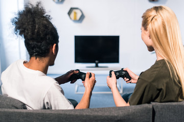 rear view of multiethnic couple playing video game together at home © LIGHTFIELD STUDIOS