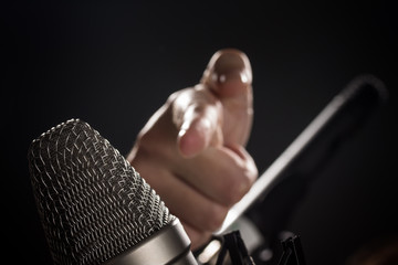 Finger zeigt auf Mikrofon